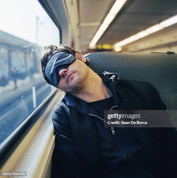 young man sleeping on train - máscara de olhos imagens e fotografias de stock