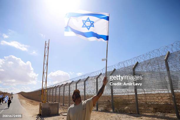Man holds up an Israeli flag as Israeli right-wing protestors, including settlers, protest and try to block aid from entering Gaza at the Nitzana...
