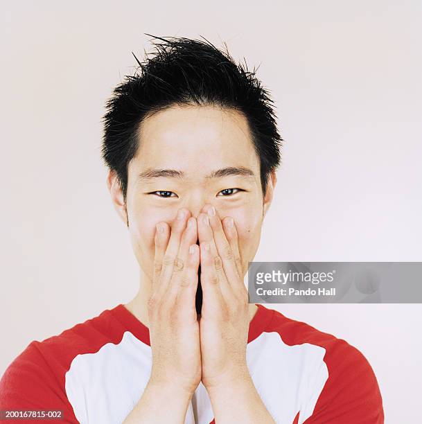 young man with hands covering mouth, portrait, close-up - 感情表現シリーズ ストックフォトと画像