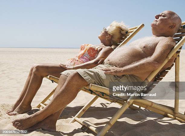senior couple sitting in chairs on beach, eyes closed - fat bald men stock pictures, royalty-free photos & images