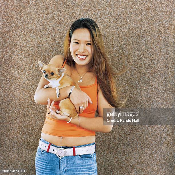 young woman holding chihuahua, smiling, portrait - frau chihuahua stock-fotos und bilder