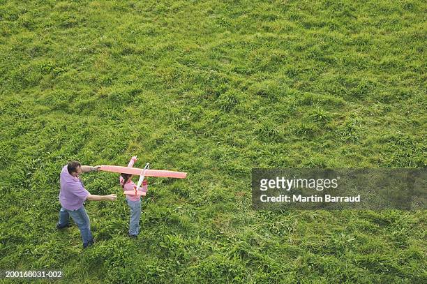 father and daughter (9-11) with model plane in field, elevated view - toy airplane stock-fotos und bilder