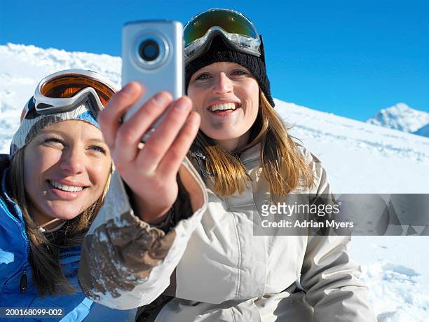 two women in ski wear taking self portrait with mobile camera phone - travel12 stock pictures, royalty-free photos & images