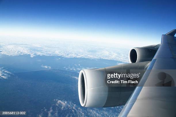 airplane wing and engine over cumulus clouds, view through window - tim flach stock-fotos und bilder