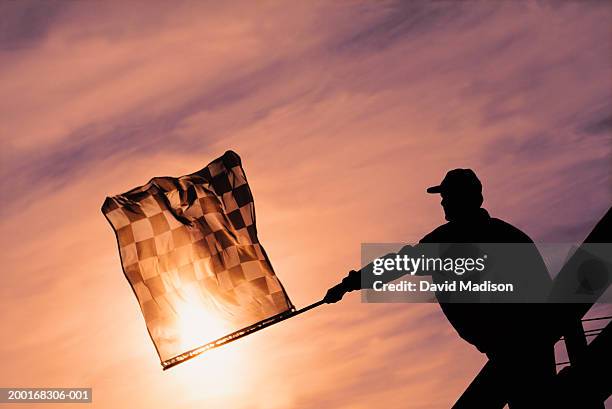 racing official waving checkered flag at finish line - drapeau à damiers photos et images de collection