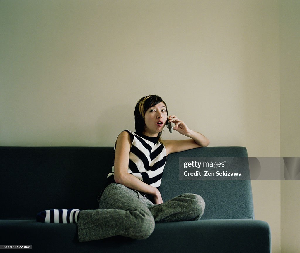 Young woman on couch using mobile phone