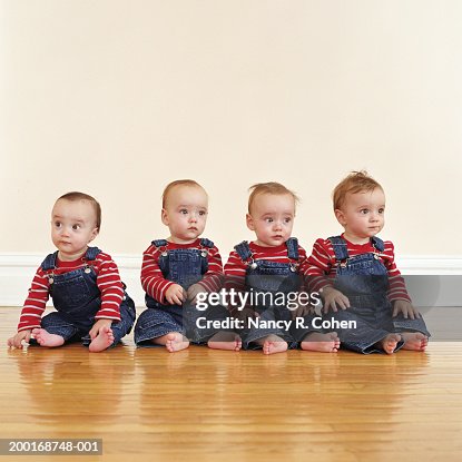 Quadruplet Babies Sitting Side By Side On Hardwood Floor High-Res