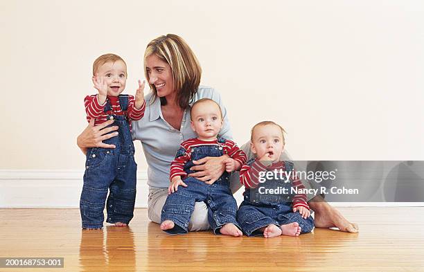 mother sitting on hardwood floor with triplet baby boys (9-12 months) - triplet stock pictures, royalty-free photos & images