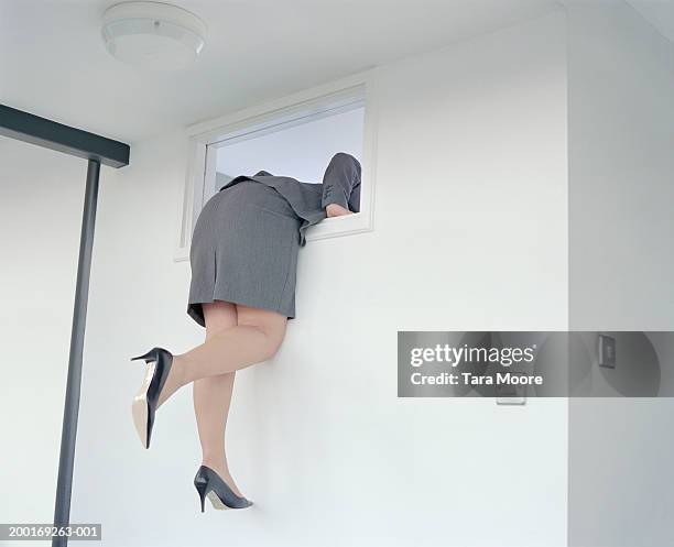 young businesswoman climbing out window, rear view - saída imagens e fotografias de stock