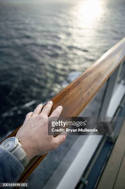 man watching sunrise from cruise ship, close-up of hand on railing - geländer stock-fotos und bilder