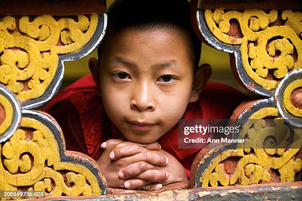bhutan, thimphu, monk (9-11) peeking through ornate carving, portrait - bhutan monk stock pictures, royalty-free photos & images