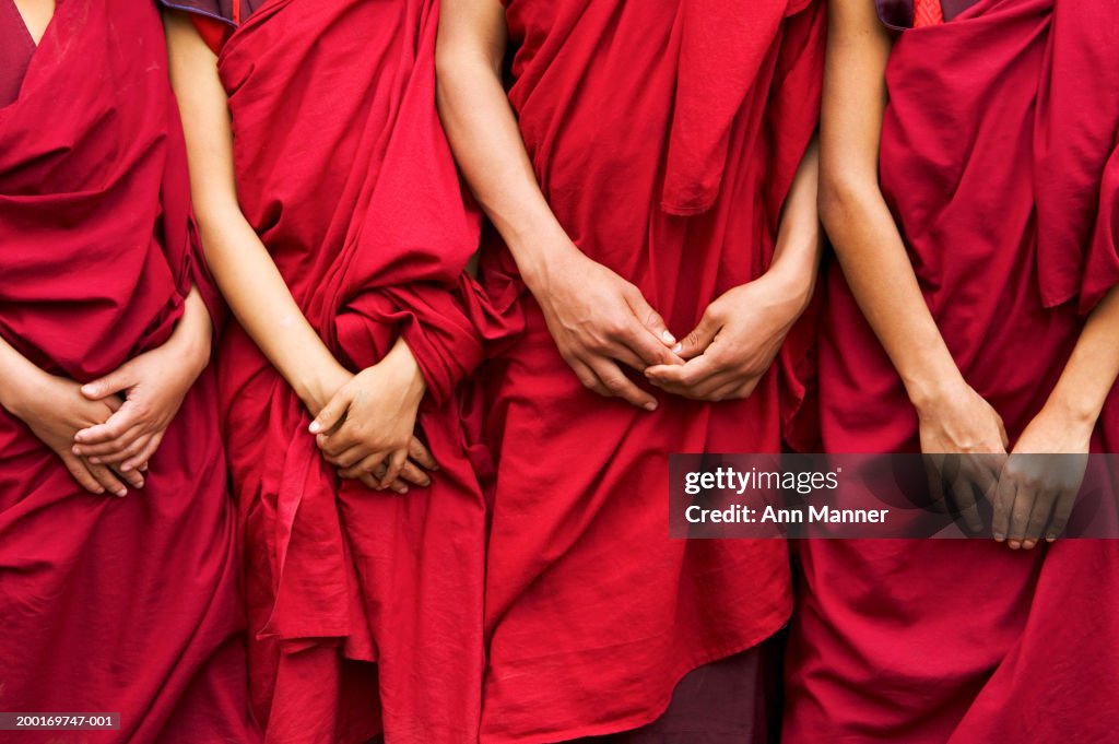 Bhutan, four monks standing side by side, hands clasped, mid section