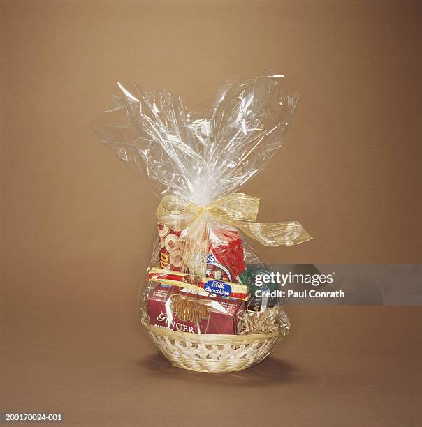 basket of cookies, chocolate and jam wrapped in cellophane - gift hamper imagens e fotografias de stock