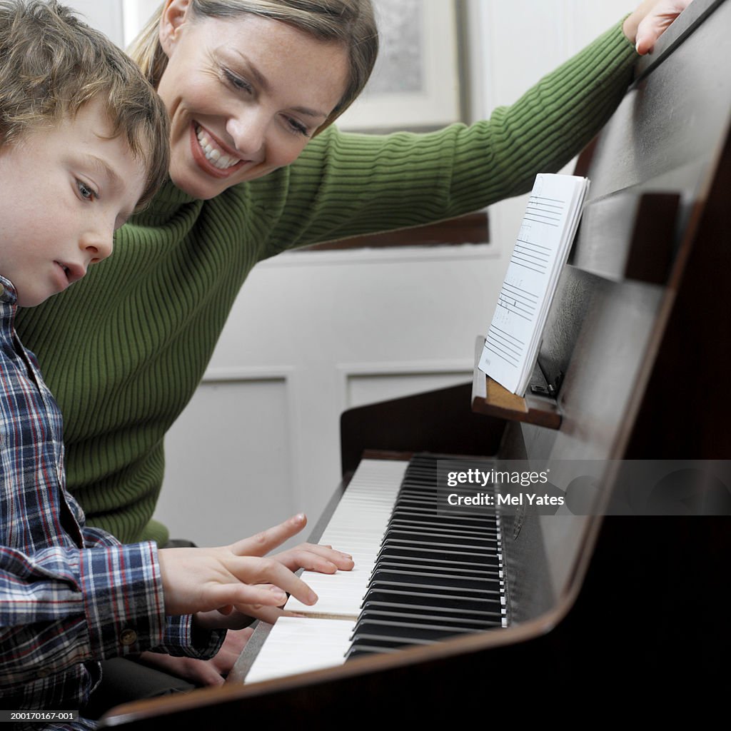 Mother watching son (4-6) playing piano, close-up