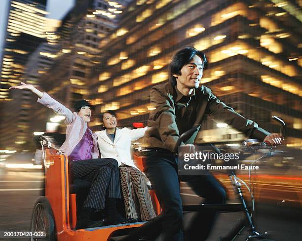 man pedaling two women in pedicab, smiling (blurred motion) - pedicab stock pictures, royalty-free photos & images