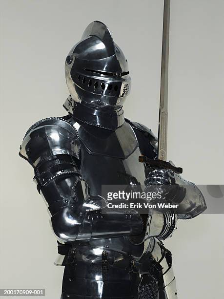 man wearing suit of armor and holding sword - armadura fotografías e imágenes de stock