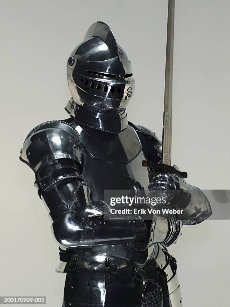 man wearing suit of armor and holding sword - armatura foto e immagini stock