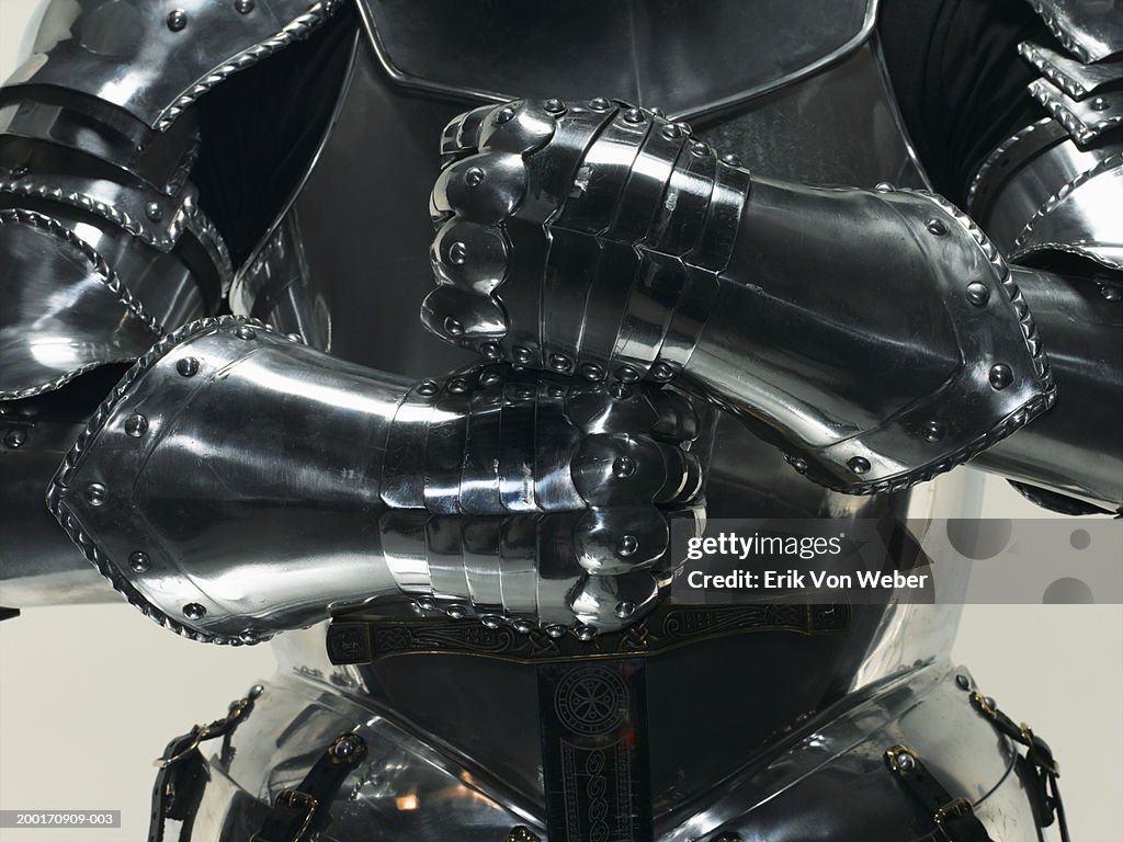 Man wearing suit of armor and holding sword, mid section