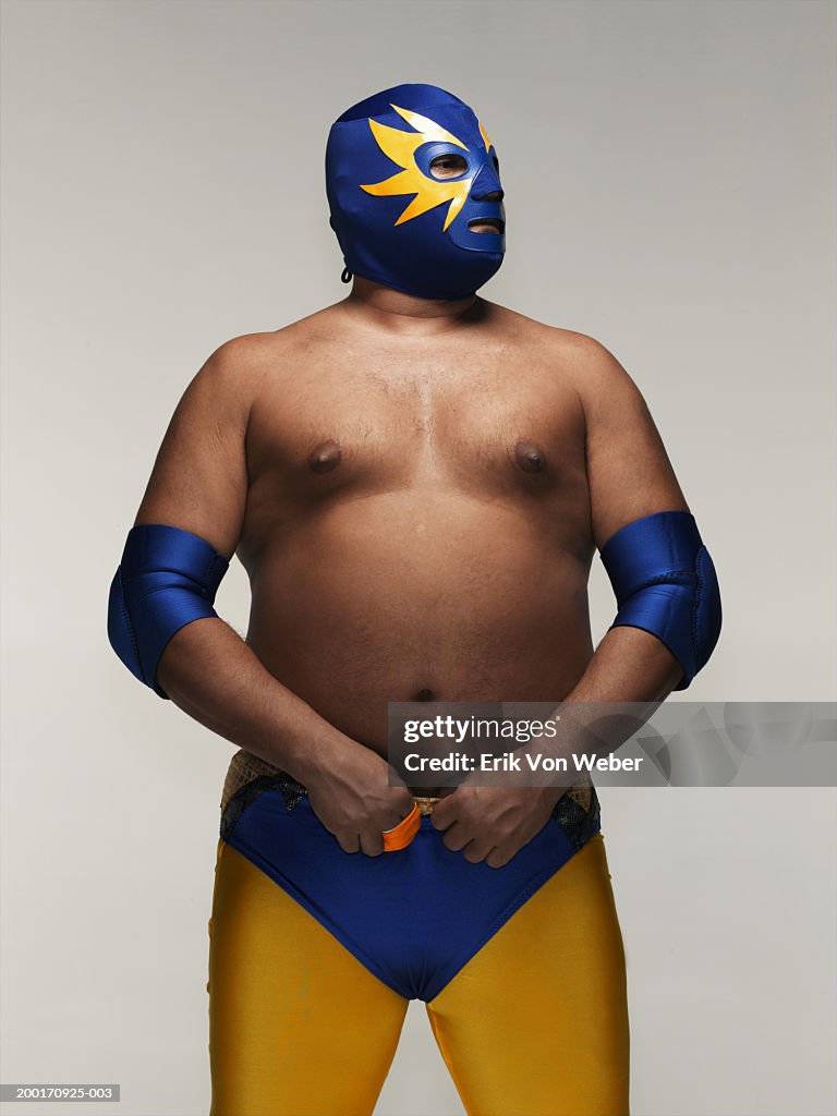 Man wearing wrestler costume and mask, looking away