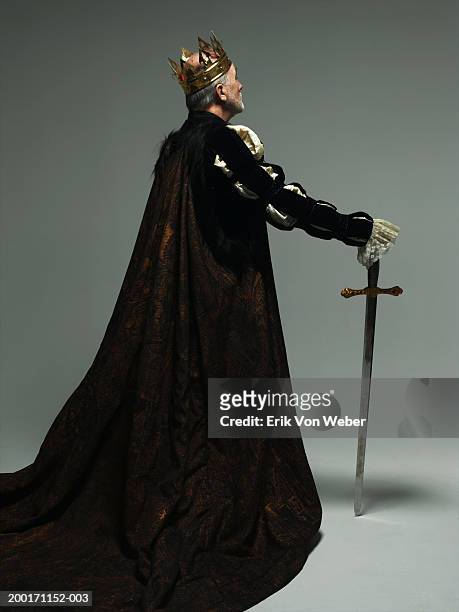 senior man wearing king costume with sword, rear view - king foto e immagini stock