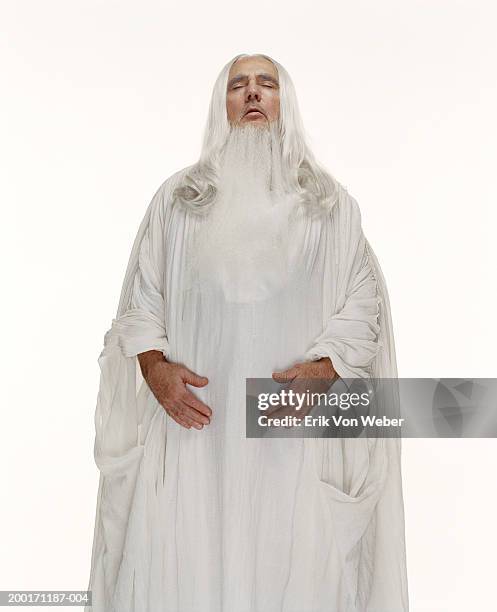 senior man wearing white robe with eyes closed - gott stock-fotos und bilder