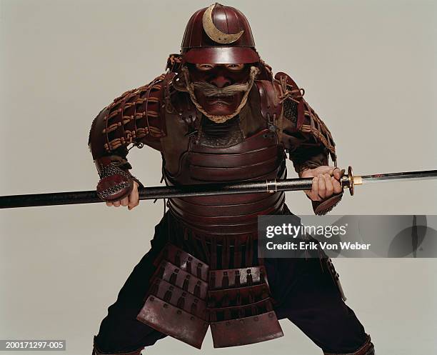 man wearing samurai costume and holding sword in fighting position - samouraï photos et images de collection