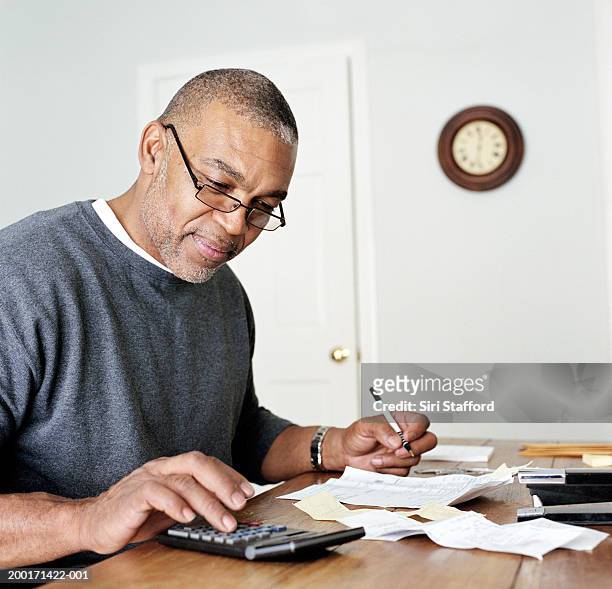 mature man doing finances in home office - home finances man stock pictures, royalty-free photos & images