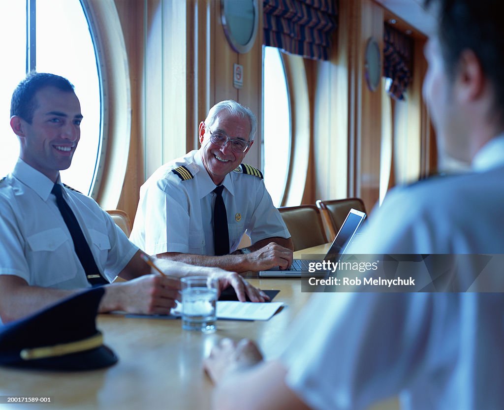 Male navy officers in meeting room, smiling