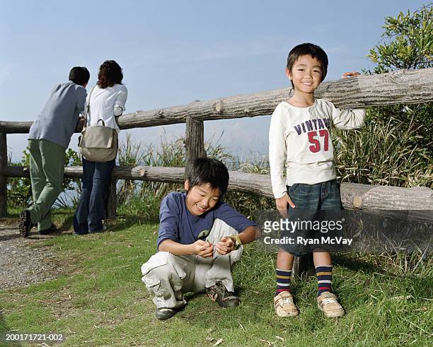 parents and two sons (5-10) beside wooden fence (focus on boys) - boy 10 11 stock pictures, royalty-free photos & images