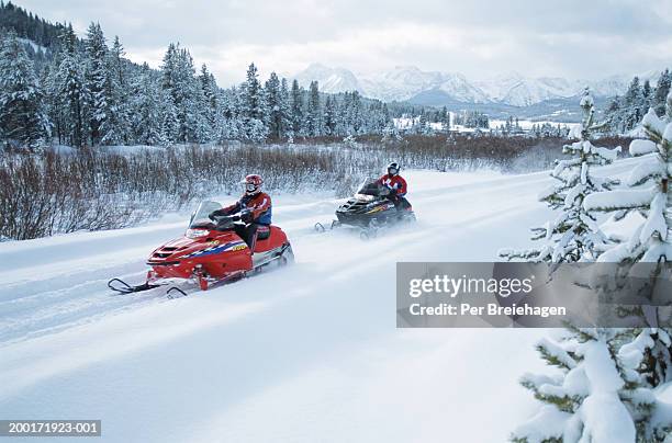 two people on snowmobiles - snow vehicle stock pictures, royalty-free photos & images