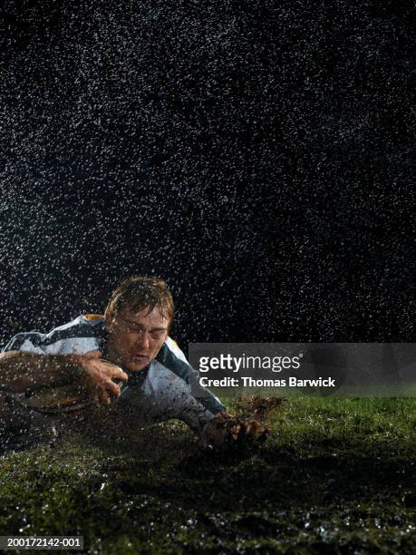 male rugby player with ball in mud on ground, night - try scoring stock pictures, royalty-free photos & images