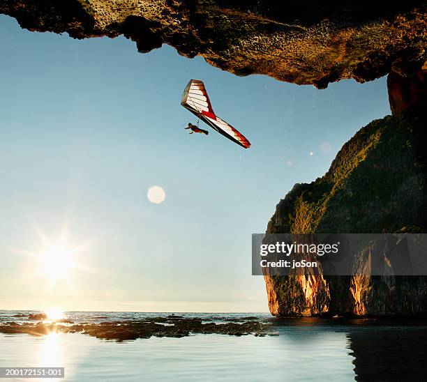 young man hang-gliding over limestone cliffs, sunset - glides stock pictures, royalty-free photos & images