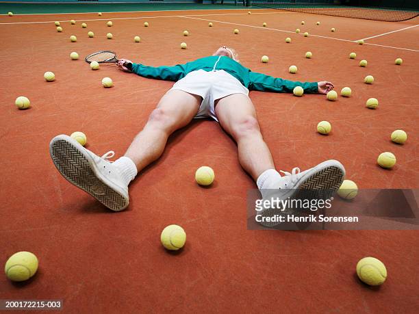 male tennis player lying on ground amongst balls - large group of objects sport stock pictures, royalty-free photos & images
