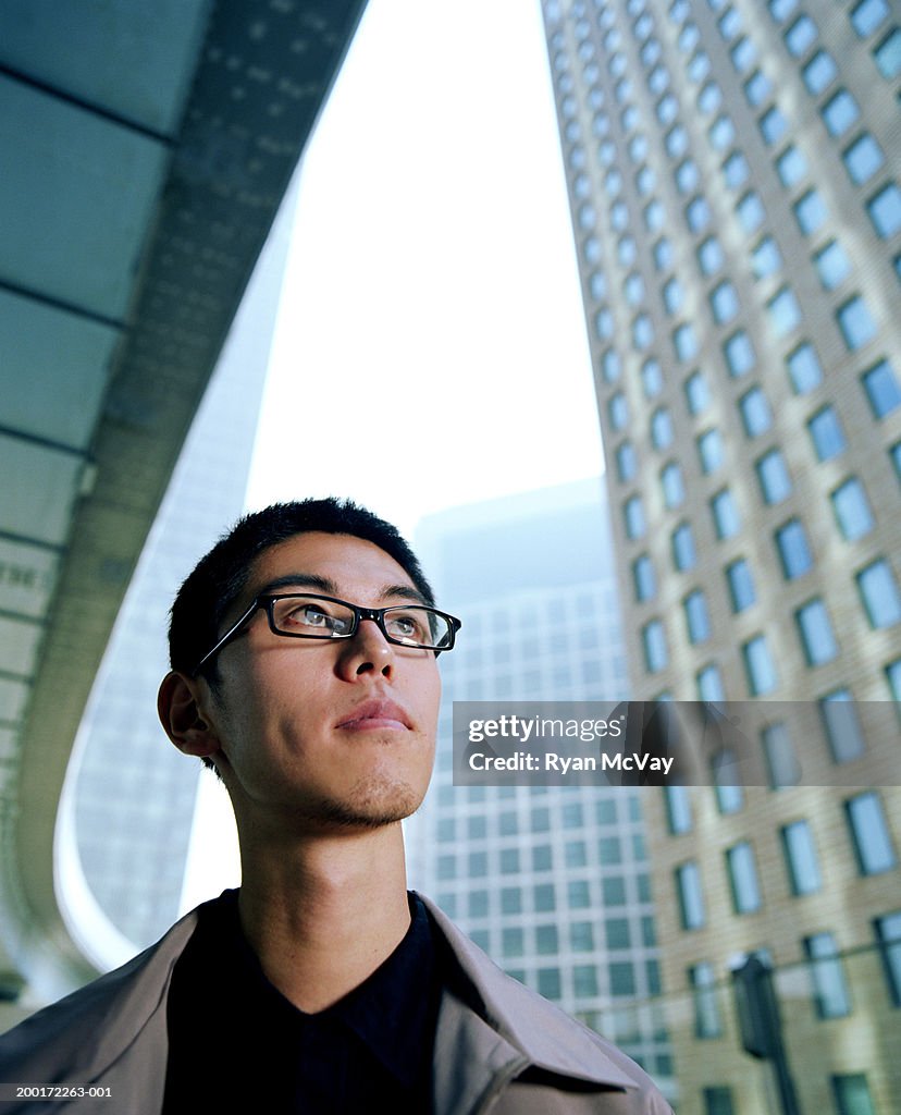Young man looking up, skyscrapers in background