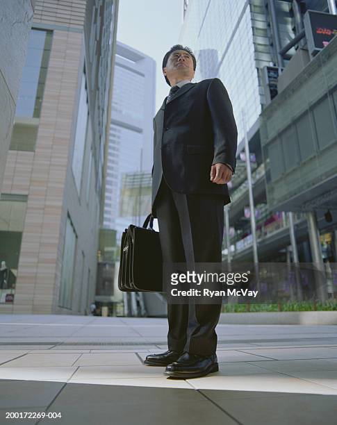 mature businessman standing on urban sidewalk, low angle view - minato stock pictures, royalty-free photos & images
