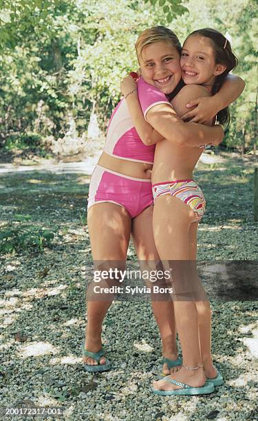 two girls (7-10) in swimsuit embraced, smiling, portrait - preteen girl swimsuit stock pictures, royalty-free photos & images