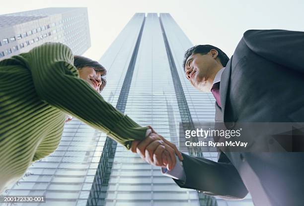man and woman shaking hands, skyscrapers in background, low angle view - nittele tower stock pictures, royalty-free photos & images