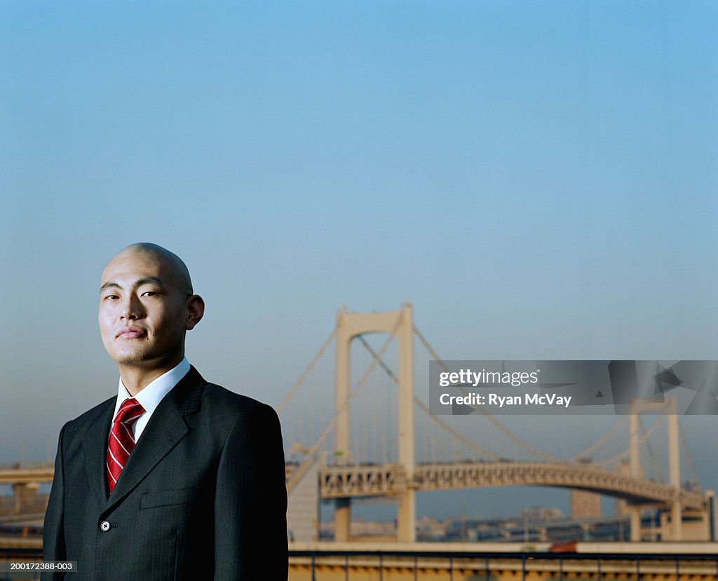 Japan, Tokyo, Odaiba, young businessman near Rainbow Bridge, portrait