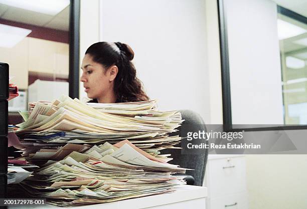 female office worker sitting at desk with pile of paperwork - formulare stock-fotos und bilder