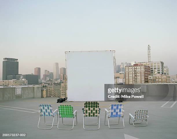 folding chairs sitting in front of projection screen on rooftop - twilight movie stock-fotos und bilder