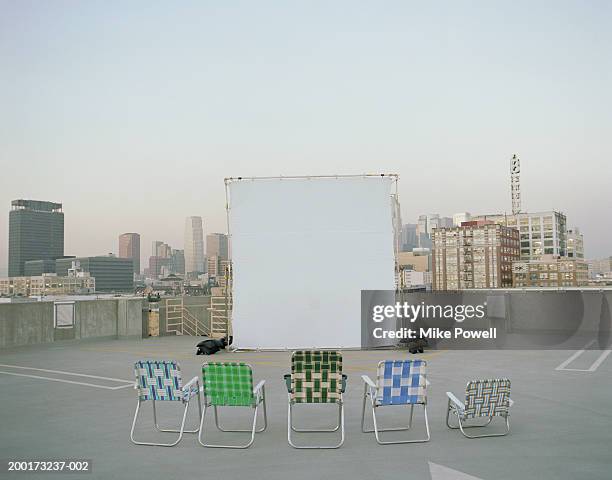 folding chairs sitting in front of projection screen on rooftop - projection film outdoor stock pictures, royalty-free photos & images