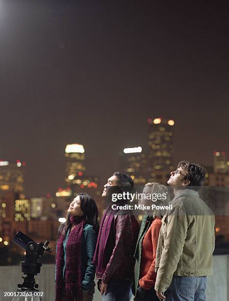 two couples on rooftop, looking upwards at night sky - astronomy stock pictures, royalty-free photos & images