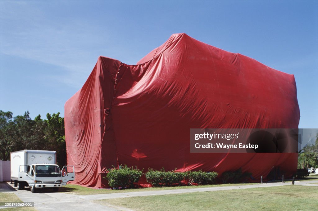 Exterminator van by building undergoing tent fumigation