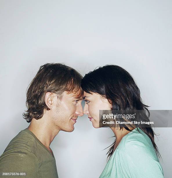 young couple looking at each other, foreheads touching, side view - faccia a faccia foto e immagini stock