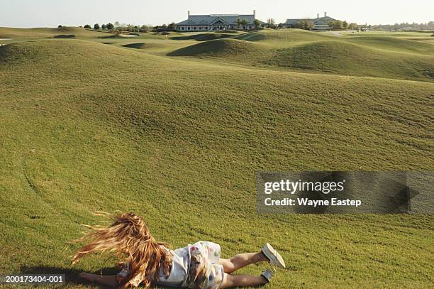 girl (6-8) rolling down slope on golf course - kids clubhouse stock pictures, royalty-free photos & images