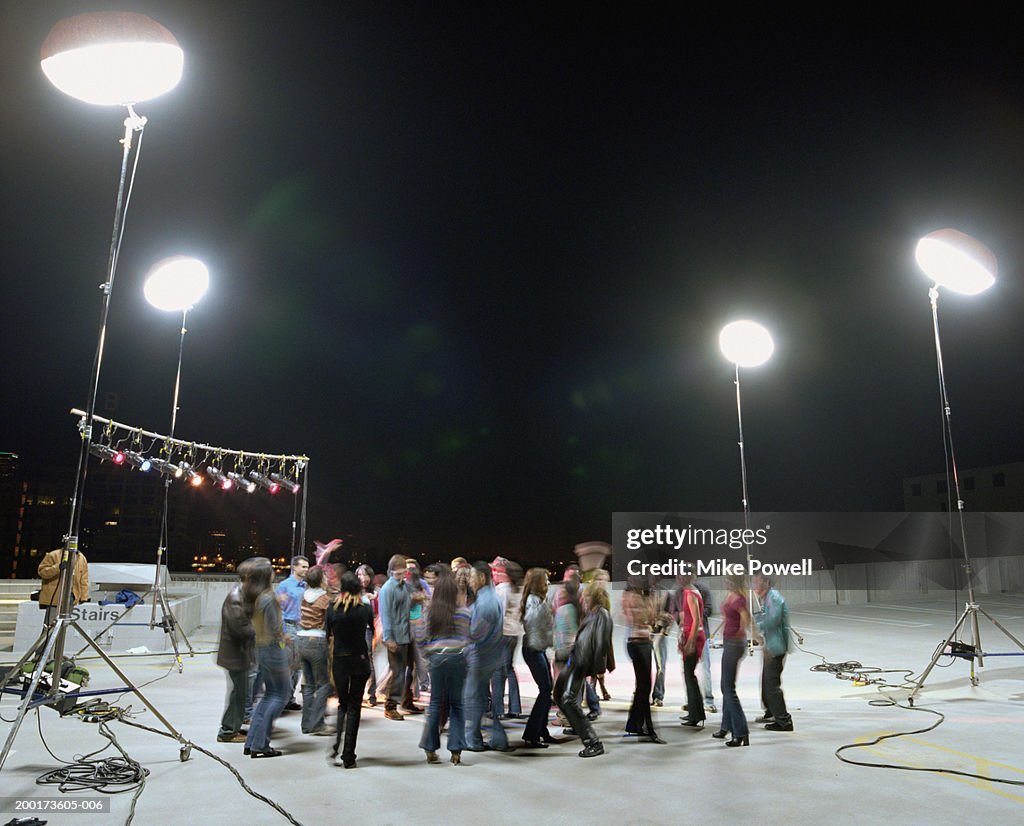 Group of young adults dancing at rooftop set (blurred motion)