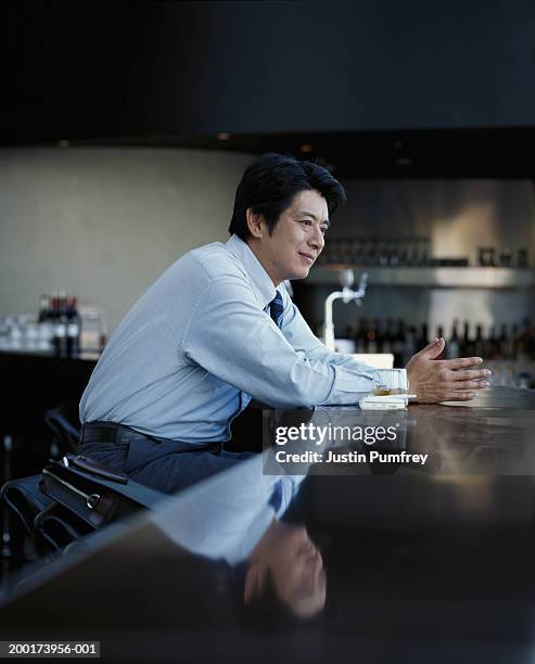 mature businessman sitting at bar, side view - 酒場　日本 ストックフォトと画像