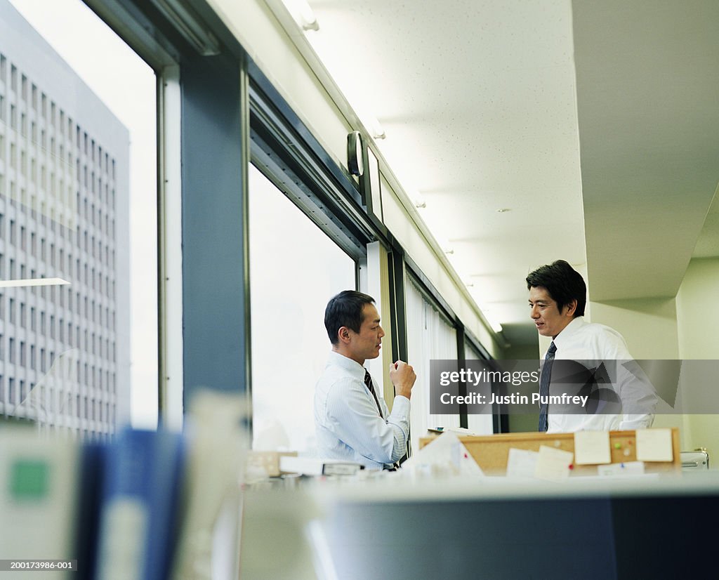 Two businessmen having discussion in office, side view