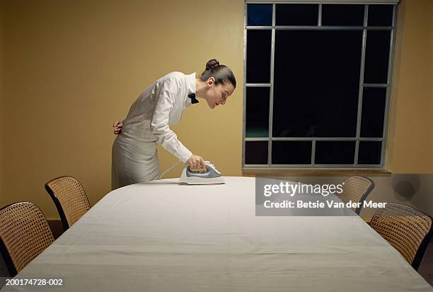 waitress ironing tablecloth on table, side view - ossessivo foto e immagini stock
