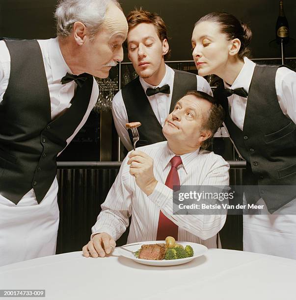 man dining, showing portion of meat on fork to waiters and waitress - disappointment stock-fotos und bilder